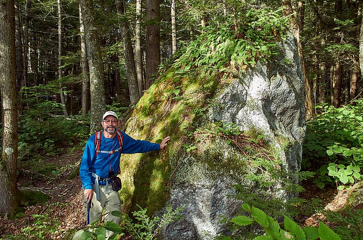 Hiker standing next to a moss-covered boulder