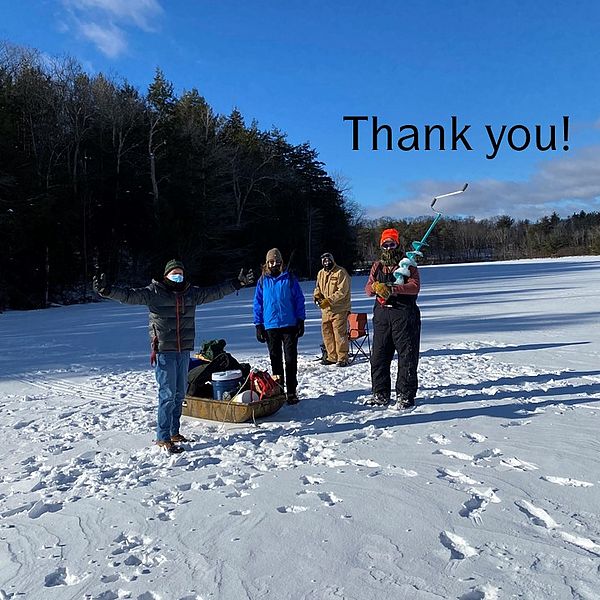 Four people standing on snow-covered frozen lake